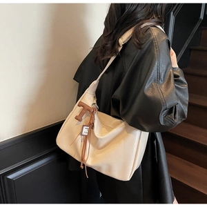 Detalle del bolso hobo grande crema con textura suave y colgante en forma de T marrón