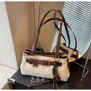 Close-up of contrast-color leather pillow bag with buckle detail and side mirror reflection
