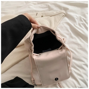 Detail einer hellrosa Tasche mit Kordelzug, Metall-Druckknopf und schwarzem Stofffutter