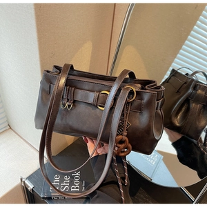 Macro detail of dark brown retro shoulder bag with glossy finish and gold ring hardware
