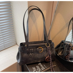Detail of vintage black matte leather shoulder bag with bronze buckle and abacus pendant