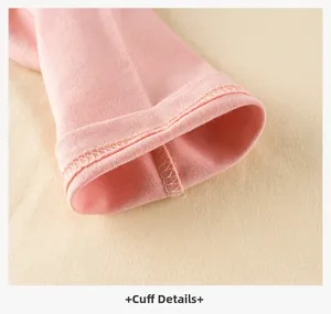 Dettaglio della maglia rosa a maniche lunghe in cotone con polsini puliti e cuciture di pregio