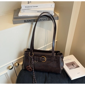 Detail of vintage brown leather pillow bag with gold ring buckle and woven tassel decoration