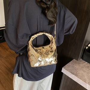 Sac à main tissé doré en cuir avec poignée et finition métallique porté par mannequin