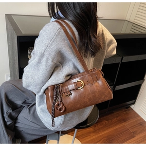 Detail of vintage brown shoulder bag with decorative leather strap and woven keychain