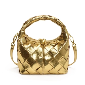 Sac à main tissé doré métallisé avec poignée et bandoulière sur fond blanc