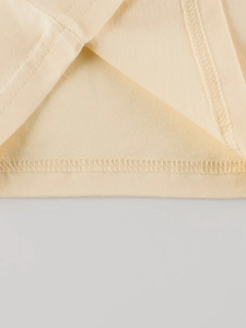 Close-up of cream color children's cotton T-shirt showing detailed double-needle hem stitching