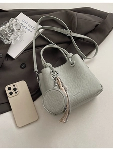 Borsa a mano verde salvia in pelle martellata con portamonete su sfondo grigio