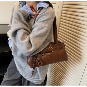 Detail of retro brown shoulder bag featuring gold buckle and woven tassel charm