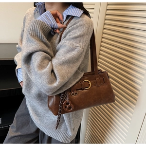Detail of vintage brown shoulder bag featuring gold buckle and woven strap accessory