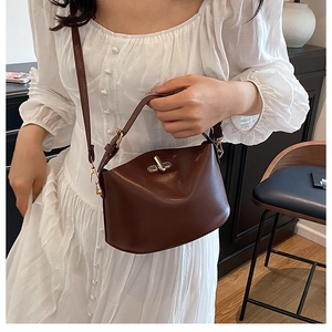 Detail of dark brown lychee leather bucket bag with gold twist lock on a vintage chair