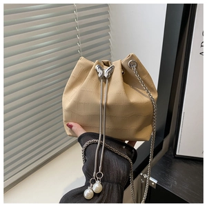 Detail of beige crocodile pattern bucket bag with butterfly clasp and pearl chain