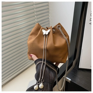 Close-up of crocodile pattern bucket bag with metal butterfly and pearl drawstring