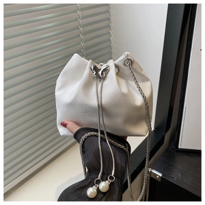 Detail of white crocodile pattern bucket bag with butterfly clasp and pearl chain