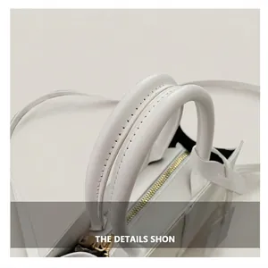 Close-up of white leather handbag handles with black stitching and gold metal zipper