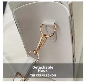 Detail showing the light gold swivel hook and detachable strap of the white leather handbag