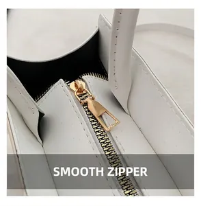 Detail view of smooth golden metal zipper and stitching on white leather crossbody bag