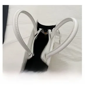 Top view of white leather handbag showing interior compartment and golden zipper closure