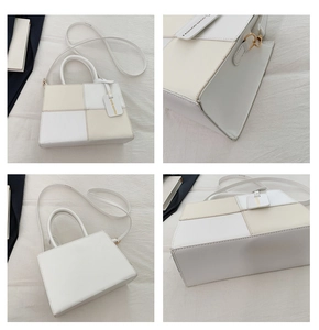 Detail view of contrast color stitching and metal hardware on a square handbag