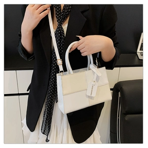 Détail d'un sac bandoulière bicolore avec étiquette FASHION BAGS sur un mannequin