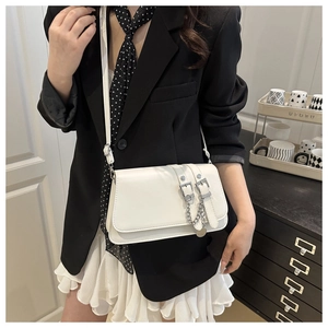 Close-up of white PU leather flap bag featuring twin buckle straps and a silver chain detail