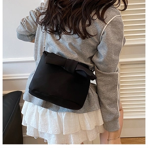 Détail d'un sac seau noir avec un grand nœud et une bandoulière chaîne métallique