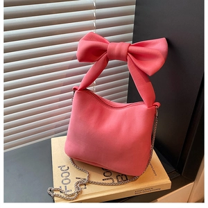 Close-up of bright pink canvas handbag with a large decorative bow and metal chain strap