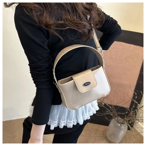 Détail du sac à main beige en similicuir avec boucle ovale en métal et logo gravé