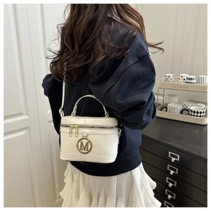 Vue détaillée d'un sac boîte en cuir blanc brillant avec logo M doré et bandoulière