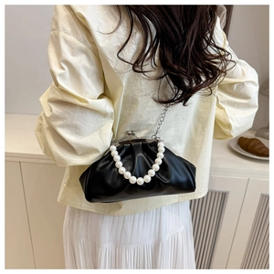 Detail of a black pleated cloud bag with elegant pearl handle and metal chain on model