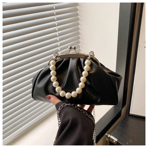 Detail of black pleated cloud bag featuring large pearl handle and silver metal clasp