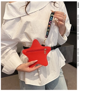 Detail of red star-shaped leather coin purse with LOVE embroidered strap worn by a model
