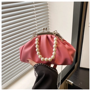 Detailed macro of pink pleated crossbody bag with pearl handle and metal clasp closure