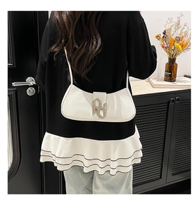 Detail of a white leather underarm bag with silver buckle worn on a shoulder