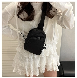 Détail du sac de poitrine en nylon noir avec fermetures éclair porté sur une robe blanche
