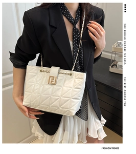 Close-up of white quilted leather texture and gold chain strap on a shoulder bag