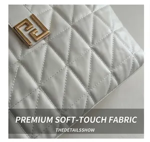Detail of white quilted leather texture with gold geometric buckle on a shoulder bag