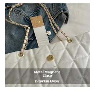 Detail of white quilted handbag featuring a golden magnetic closure and chain strap