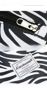 Détail de la fermeture éclair en métal et du logo sur le grand sac de voyage zébré