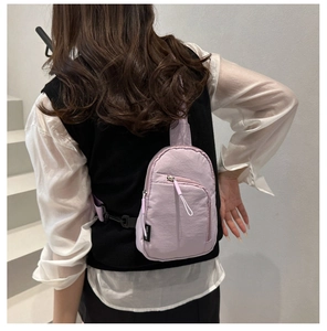 Vue détaillée d'un sac de poitrine en nylon lilas avec des fermetures éclair en métal