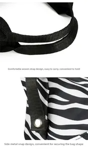 Detail of cow print travel bag featuring sturdy black handles and side metal snap buttons