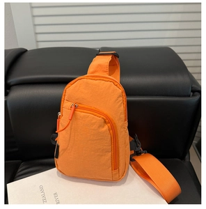Close-up of bright orange nylon crossbody bag with adjustable strap and zip pockets