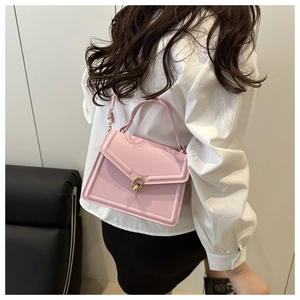 Pink rectangular crossbody bag with golden horsebit buckle shown on a female model