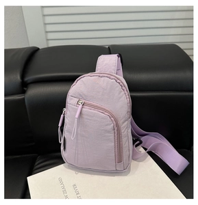 Detailed view of purple nylon crossbody bag with zipper compartments and adjustable strap