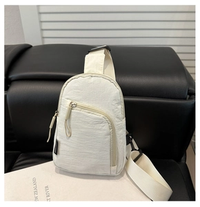 Detail of off-white crinkled nylon sling bag with adjustable strap on leather seat