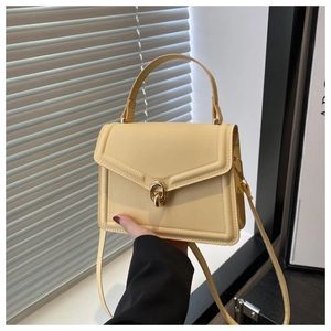 Détail du sac à bandoulière en cuir jaune crème avec un fermoir rotatif en métal doré