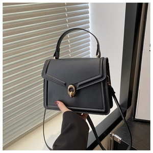 Détail du sac en cuir noir avec fermoir rotatif doré circulaire et poignée supérieure