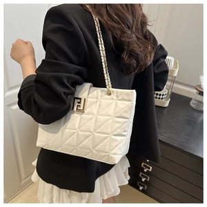 Rear view of model holding a white quilted shoulder bag with gold chain and metal buckle