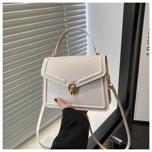 Détail du sac à main blanc crème avec coutures en V et anneaux dorés entrelacés