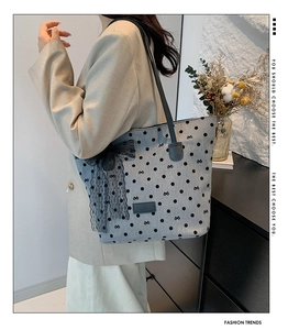 Borsa tote a pois con grande fiocco di pizzo indossata a spalla su un abito beige